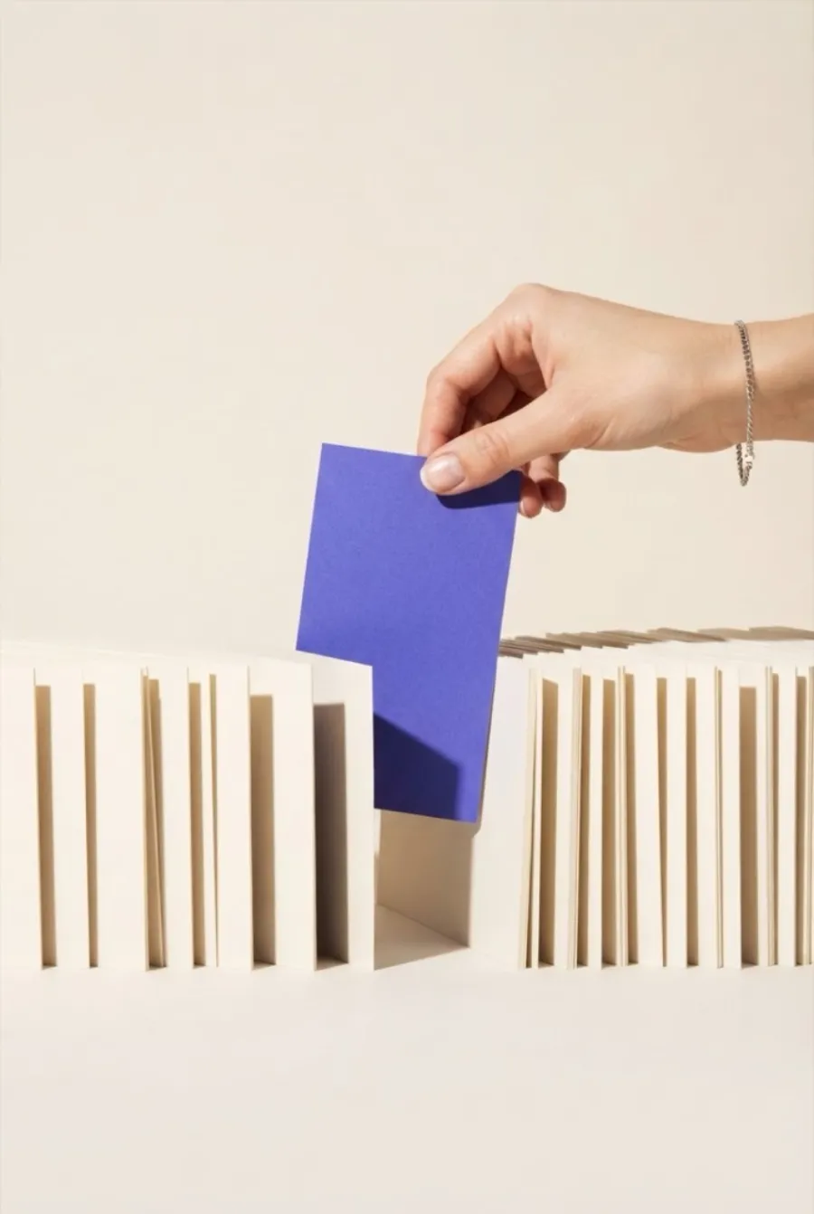 Eine Hand zieht eine lila Karte aus einer dicht gepackten Reihe heller Karten